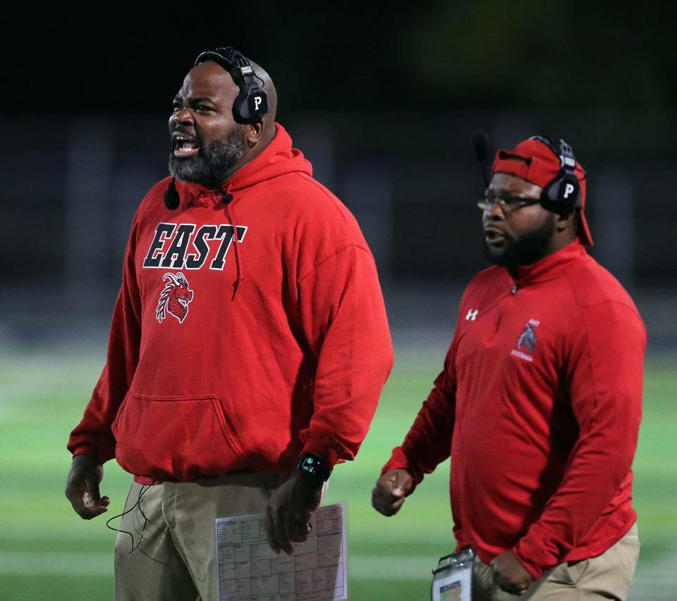 East football coach Marques Hayes, left, gets his players fired up during the first half of a Division III playoff football game against Canfield on Friday in Akron.