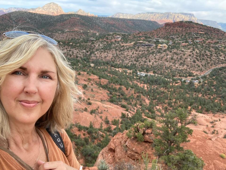 Author Courtenay Rudzinski taking a selfie with red rocks and trees in Arizona