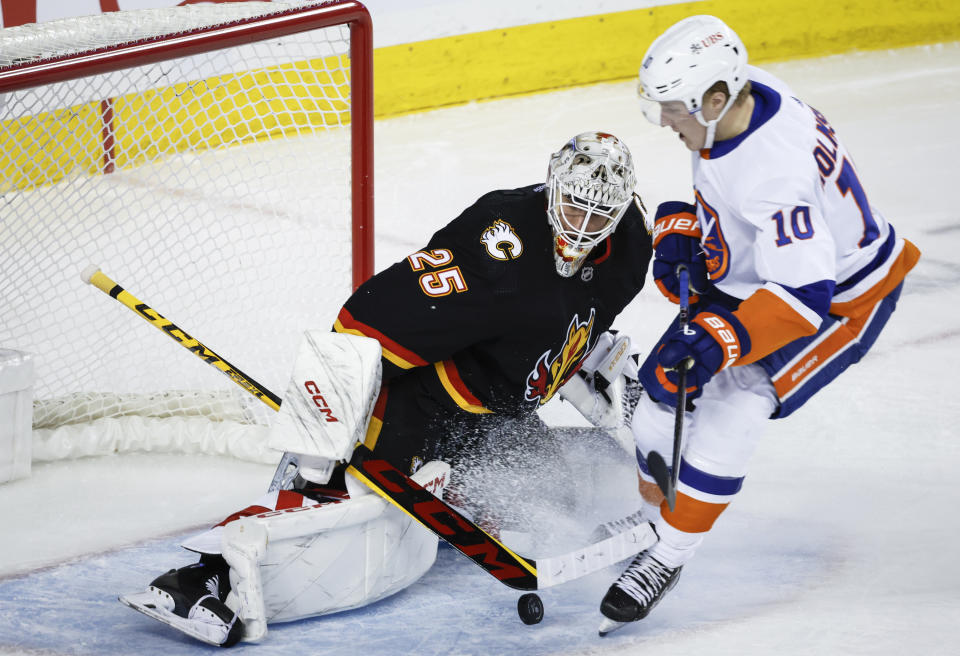 New York Islanders forward Simon Holmstrom, right, chases the puck as Calgary Flames goalie Jacob Markstrom swats it away during the second period of an NHL hockey game in Calgary, Alberta, Saturday, Nov. 18, 2023. (Jeff McIntosh/The Canadian Press via AP)