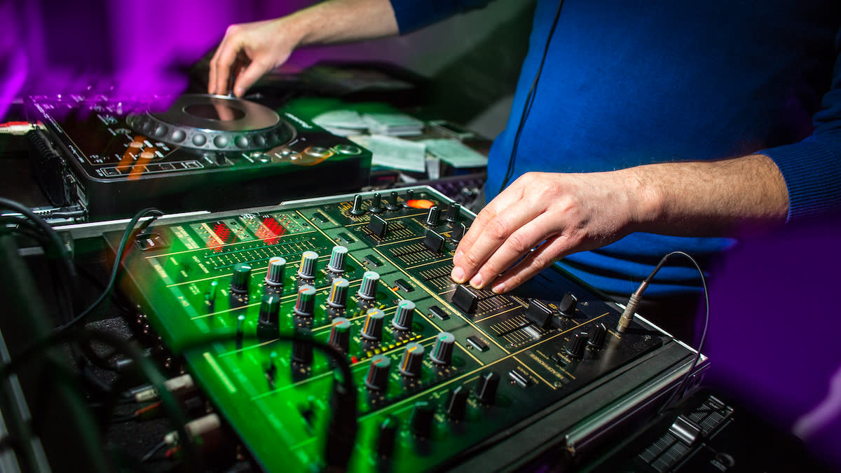  Close-up of hands on a DJ mixer and controller 