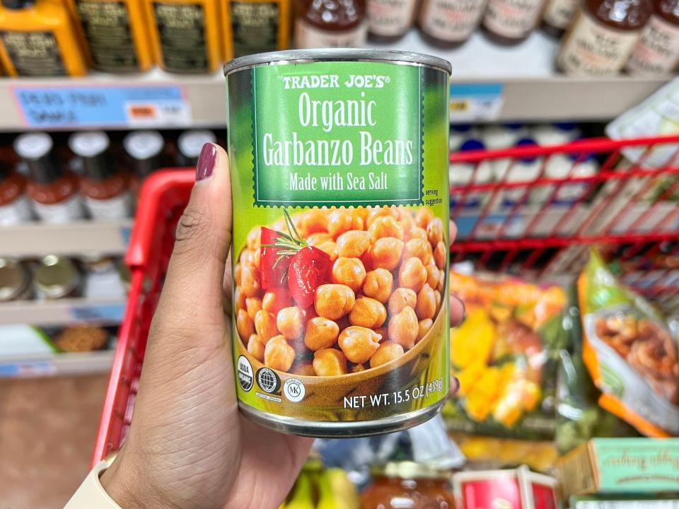 A hand holding a can of Trader Joe's organic garbanzo beans made with sea salt. 