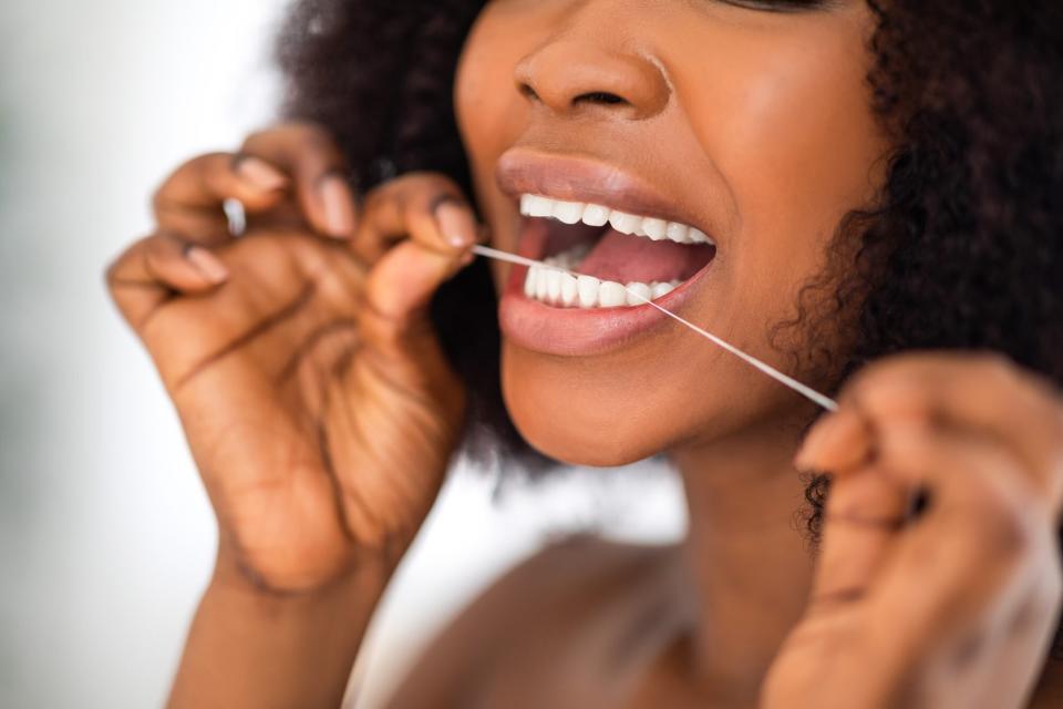 woman cleaning teeth with dental floss at home, closeup.