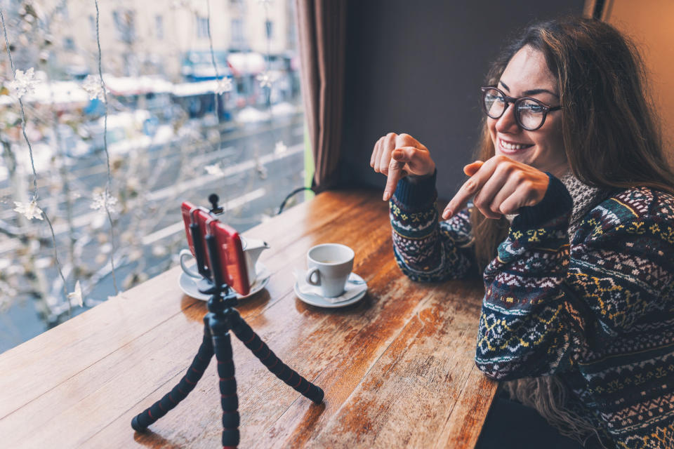 A woman sitting at a coffee shop with a tripod set up in front of her.