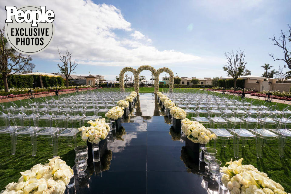<p>The ceremony was held outside at the seaside hotel, and a 100-foot long, glossy black aisle lead up to the altar, lined with all-white bouquets of roses, orchids, tulips, lisianthus and hydrangeas.</p> <p>A large flower arch was set at the beginning of the aisle, and three intertwined arches framed the altar.</p>