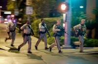 FILE - In this Oct. 1, 2017, file photo, police run toward the scene of a shooting near the Mandalay Bay resort and casino on the Las Vegas Strip in Las Vegas. Two years after a shooter rained gunfire on country music fans from a high-rise Las Vegas hotel, MGM Resorts International reached a settlement that could pay up to $800 million to families of the 58 people who died and hundreds of others who were injured, attorneys announced Thursday, Oct. 3, 2019. (AP Photo/John Locher, File)