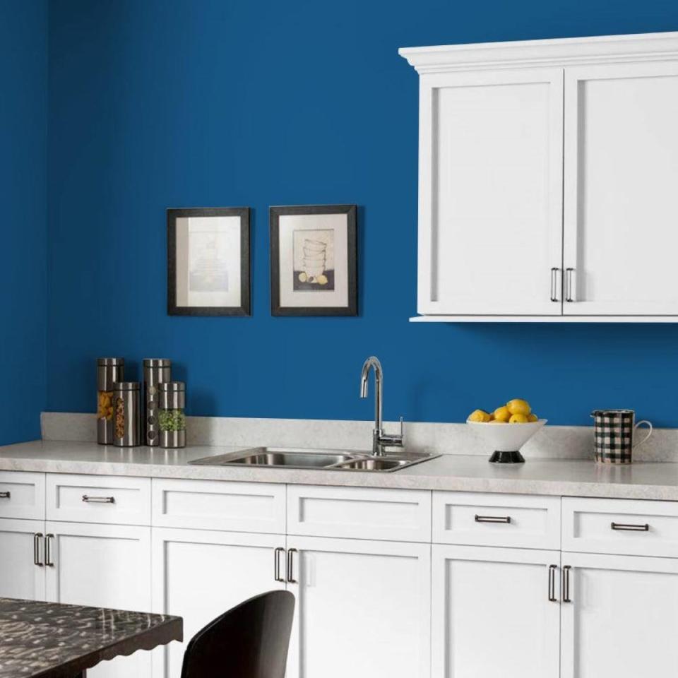 Kitchen with white cabinets and PPG's Stunning Sapphire dark blue walls.