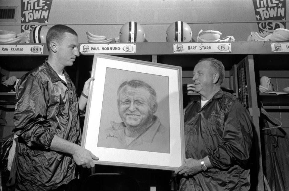 John Gordon, left, designed the iconic Green Bay Packers "G" logo that has become one of the most well-known logos in the NFL. In this 1962 photograph, Packers equipment manager Gerald "Dad" Braisher looks at a portrait of himself painted by Gordon, who was Braisher’s assistant as well as a St. Norbert College art student at the time the football shaped “G” was designed and selected to be the Packers logo. The “G” has been on the Packers football helmets since 1961.
