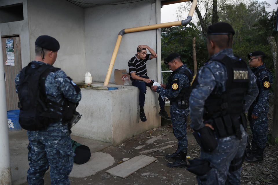 Agentes de la Policía Nacional guatemalteca comprueban la documentación de un migrante hondureño que intenta llegar a Estados Unidos, en El Cinchado, Guatemala, en la frontera con Honduras, el miércoles 15 de enero de 2020. (AP Foto/Moisés Castillo)