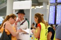 Passengers talk to Civil Aviation Authority employees at Mallorca Airport as an announcement is expected on the Thomas Cook's tour operator, in Palma de Mallorca