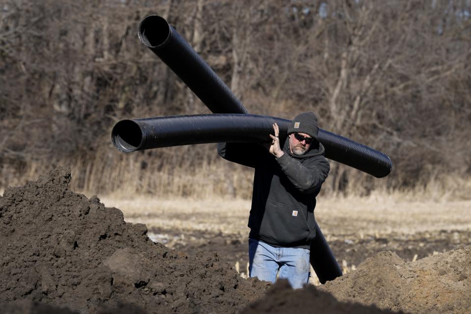 A worker installs parts that will be used with a bioreactor, Friday, Feb. 10, 2023, near Nevada, Iowa. Simple systems called bioreactors and streamside buffers help filter nitrates from rainwater before it can reach streams and rivers. (AP Photo/Charlie Neibergall)