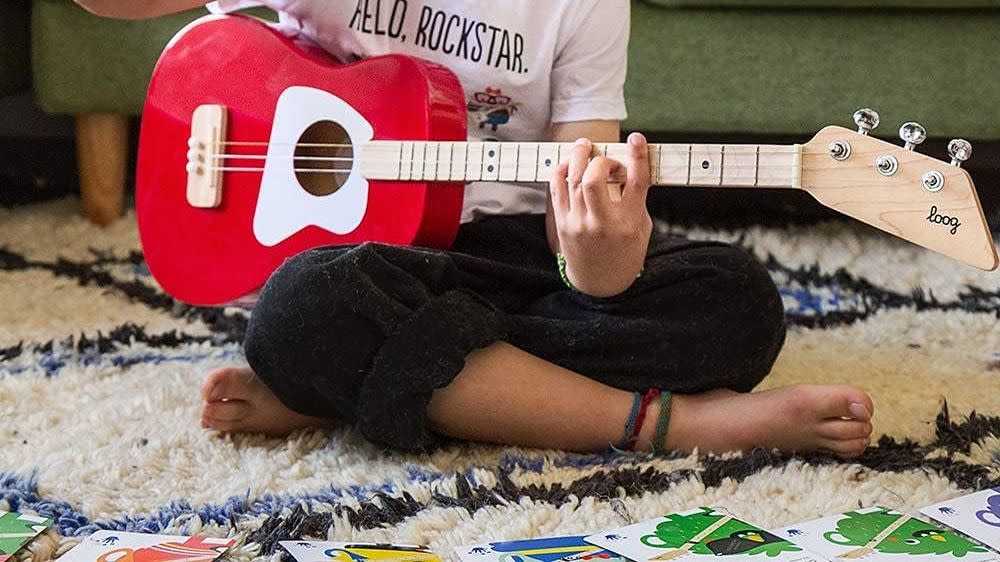 boy playing red guitar on carpet