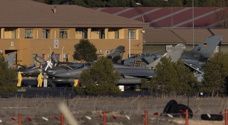 People in protective suits work near damaged fighter planes at Los Llanos military base in Albacete on January 27, 2015