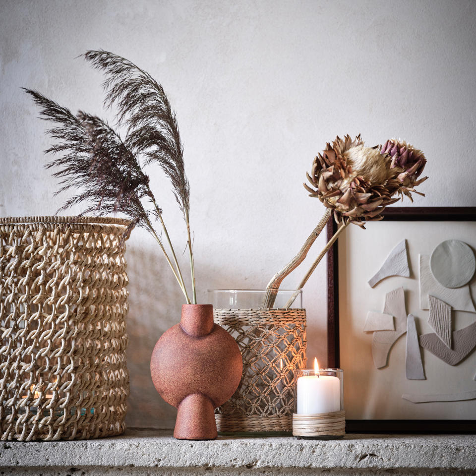 Stone shelf with vases, art and burning candle