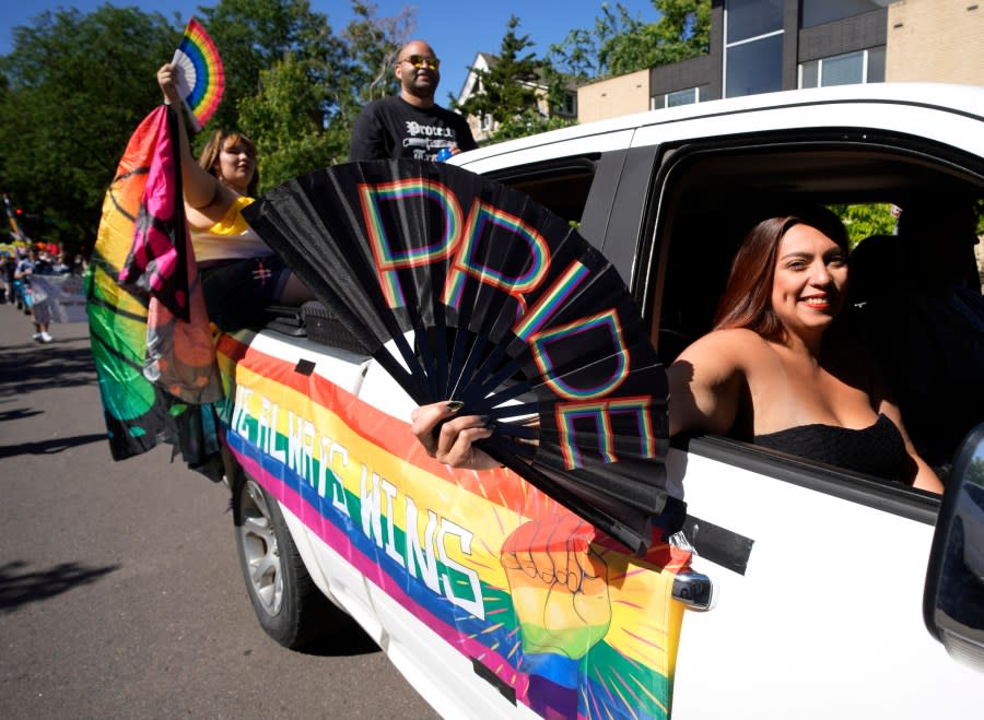 A participant waves a fan while riding in a float to take part in the Pride parade through the streets of downtown Sunday, June 25, 2023, in Denver. (AP Photo/David Zalubowski)