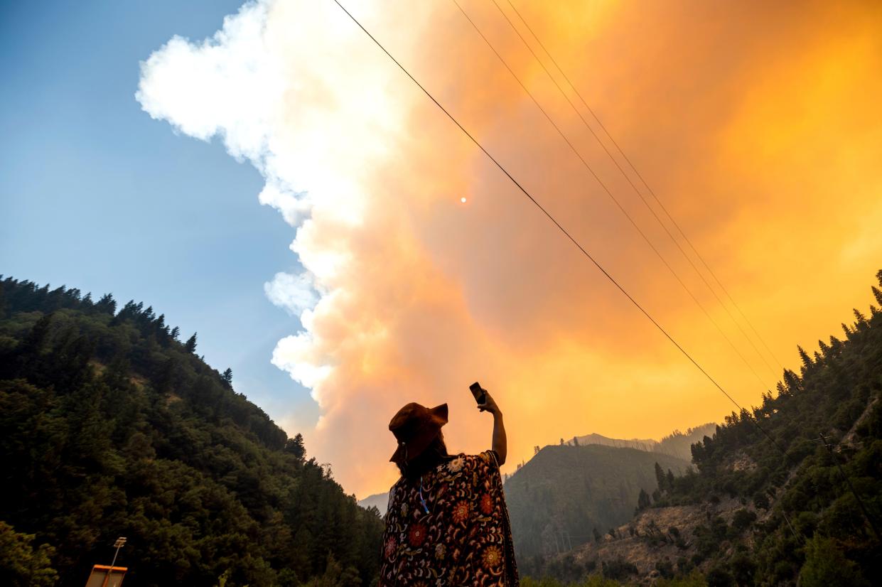 Jessica Bell takes a video as the Dixie Fire burns along Highway 70 in Plumas National Forest, Calif. on Friday, July 16, 2021.