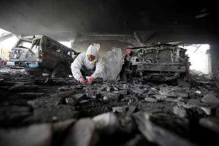 A forensic expert invistigates the scene at the community hall where Saudi-led warplanes struck a funeral in Sanaa, the capital of Yemen, October 9, 2016. REUTERS/Khaled Abdullah