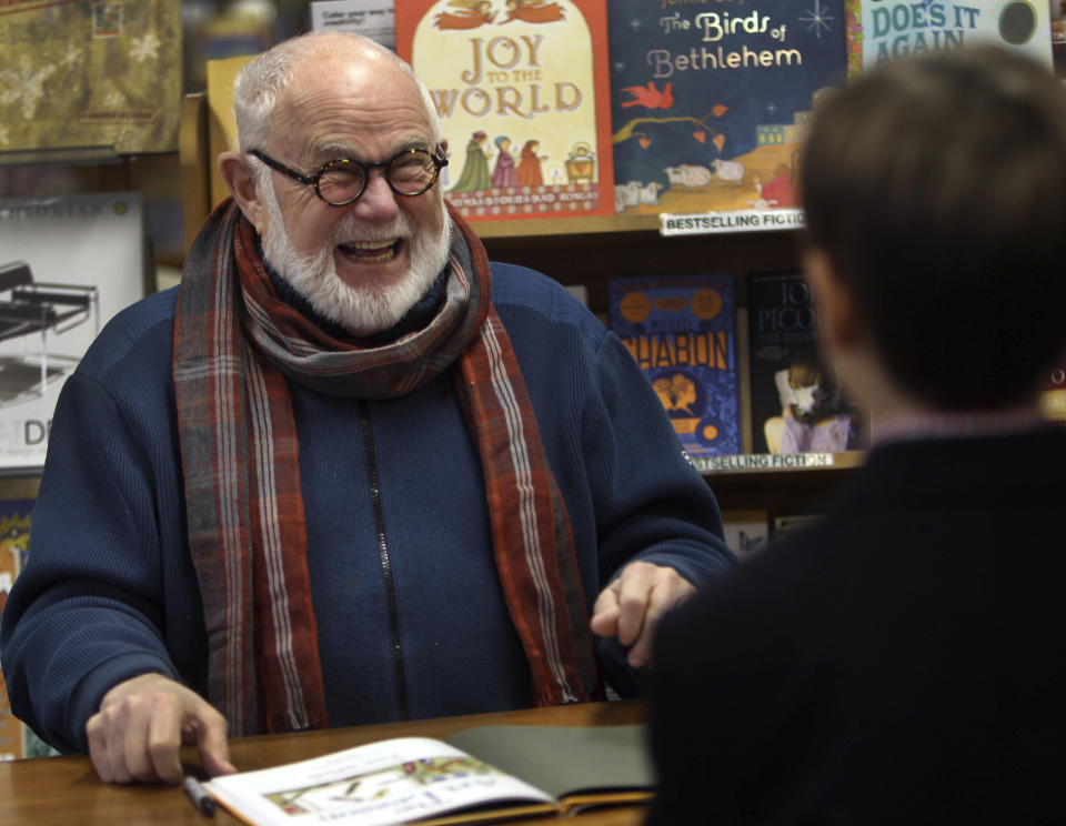 In this photo taken Sunday Dec. 1, 2013, Tomie dePaola laughs as he signs books at the Morgan Hill Bookstore in New London, N.H. The beloved children's author and illustrator has died at the age of 85. DePaola delighted generations with tales of Strega Nona, the kindly and helpful old witch in Italy. His literary agent says dePaola died Monday from surgery complications after taking a bad fall last week. (AP Photo/Jim Cole, File)