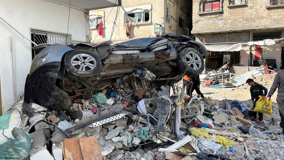 A crushed car on top of rubble outside Kamal Adwan Hospital. - Fadi Alwhidifa/Reuters