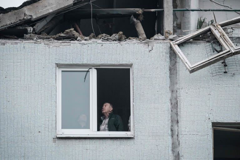 Una pareja mira una ventana rota en un edificio residencial alcanzado por un ataque con misiles en Kharkiv el 21 de septiembre de 2022, en medio de la invasión rusa de Ucrania. 