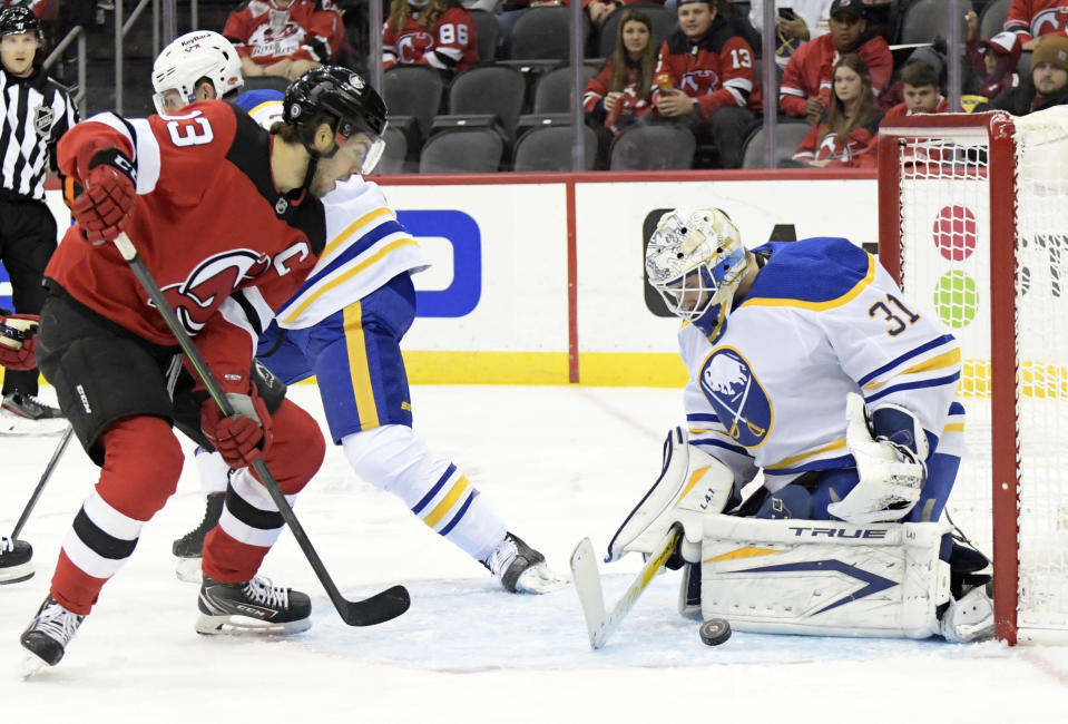 Buffalo Sabres goaltender Dustin Tokarski (31) deflects the puck on a shot by New Jersey Devils center Nico Hischier (13) during the first period of an NHL hockey game Saturday, Oct. 23, 2021, in Newark, N.J. (AP Photo/Bill Kostroun)