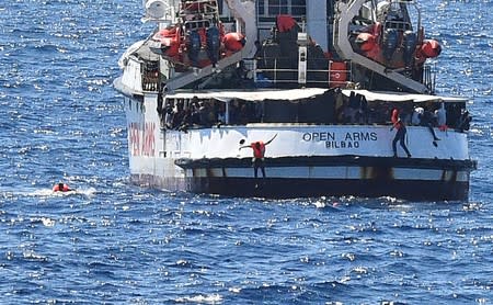 Migrants jump off the Spanish rescue ship Open Arms, close to the Italian shore in Lampedusa