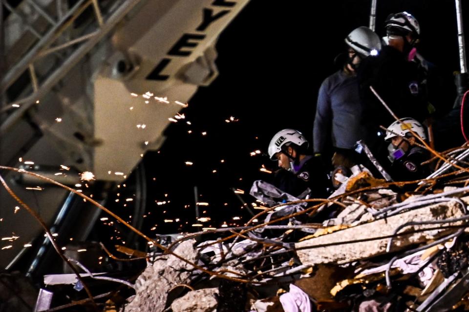 Rescuers in helmets are seen amid twisted wreckage.