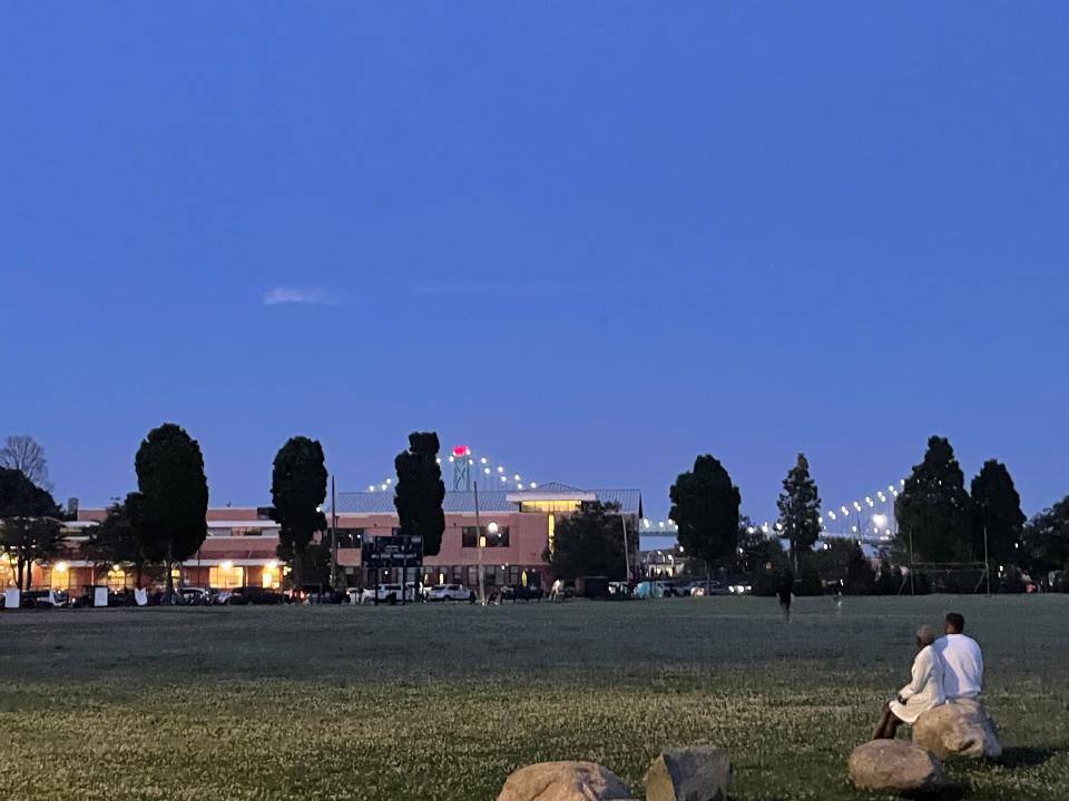 A couple sits in a field at Clark Park in Detroit, hoping for a view of the Ford Fireworks on Monday, June 25, 2024.