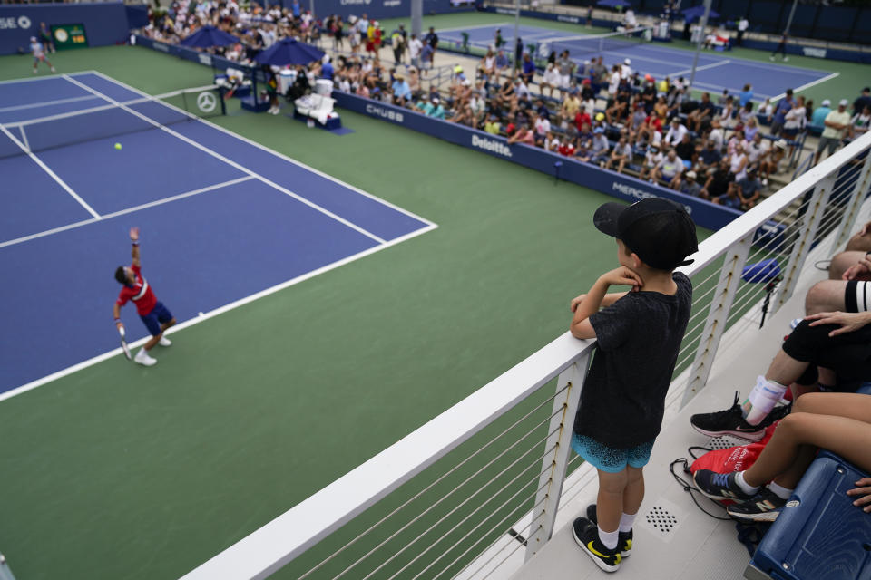 Tennis fans watch as Ricardas Berankis, of Lithuania, serves to Diego Schwartzman, of Argentina, during the first round of the US Open tennis championships, Monday, Aug. 30, 2021, in New York. (AP Photo/John Minchillo)