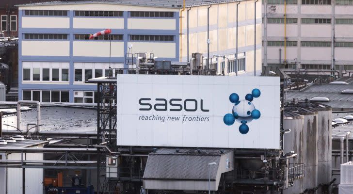 A photo of a billboard on the side of a factory that says "Sasol, reaching new frontiers"