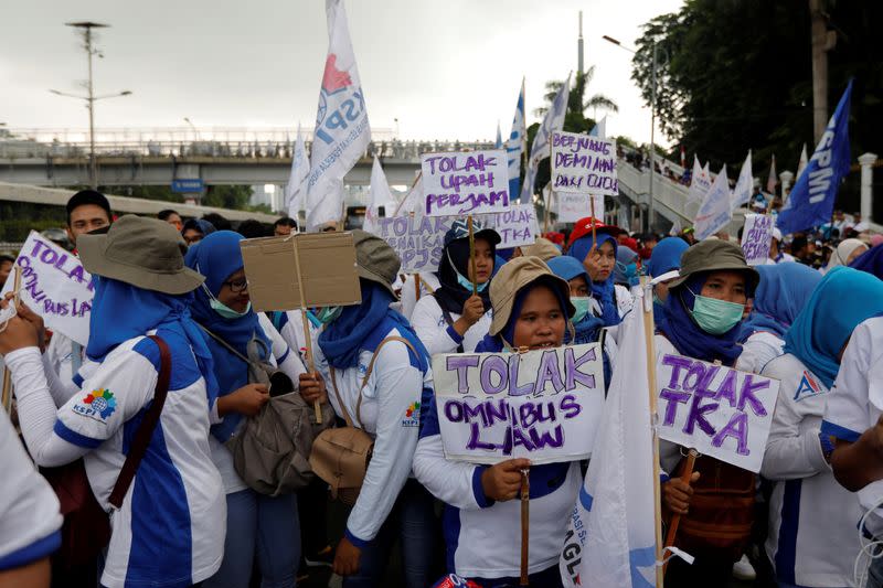 Women laborers carry placards written 'Againts Omnibus Law and Foreign Workers' as they take part during a protest outside Indonesia's parliament building in Jakarta