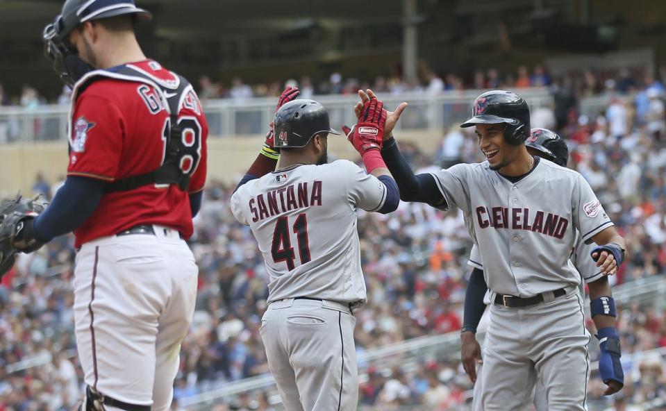 Cleveland Indians' Carlos Santana, center, is welcomed by pinch runner Oscar Mercado, right's Santana scores on his grand slam off Minnesota Twins pitcher Taylor Rogers in the 10th inning of a baseball game Sunday, Aug. 11, 2019, in Minneapolis. The Indians won 7-3. At left is Twins catcher Mitch Garver. (AP Photo/Jim Mone)