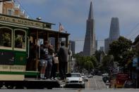 The Transamerica Pyramid building is seen as tourists ride a cable car in downtown San Francisco