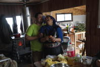 Millaray Huichalaf, a Mapuche machi, or healer and spiritual guide, laughs with her husband, Jaime Uribe Montiel, while preparing dinner at their home in Carimallin, southern Chile, on Tuesday, June 28, 2022. Huichalaf was jailed for several months for leading an occupation of the site of a proposed hydroelectric plant. But she says she doesn't fear prison because she managed to save the site, where she gathers medicinal herbs and performs sacred ceremonies. (AP Photo/Rodrigo Abd)