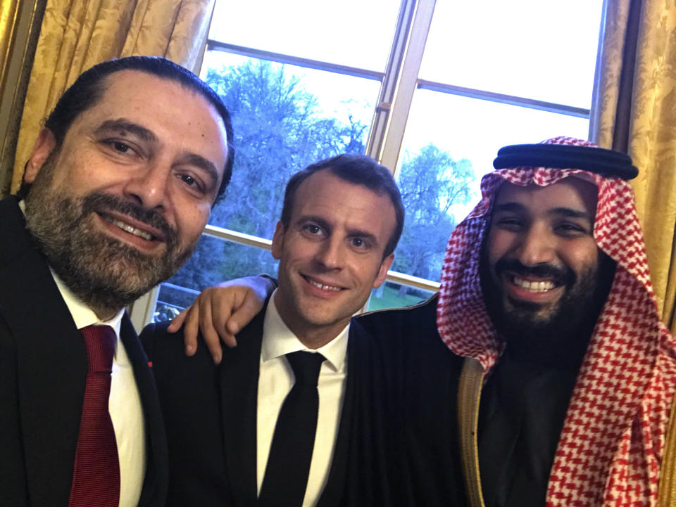 FILE - This photo released on the official twitter page of Lebanese Prime Minister Saad Hariri on Monday, April 9, 2018, shows Hariri, left, taking a selfie photo with French President Emmanuel Macron, center, and Saudi Arabia's Crown Prince Mohammed bin Salman, right, in the King George V Hotel, in Paris, France. Televised comments by George Kordahi, a Lebanon Cabinet minister about the war in Yemen exposed the depth of the crisis with Saudi Arabia, once a strong ally that poured millions and offered unwavering political support in this small Mediterranean nation. The crisis over veered into diplomatic isolation of Lebanon and threatens to split a new coalition government tasked with halting the country’s economic meltdown. (Saad Hariri via AP, File)
