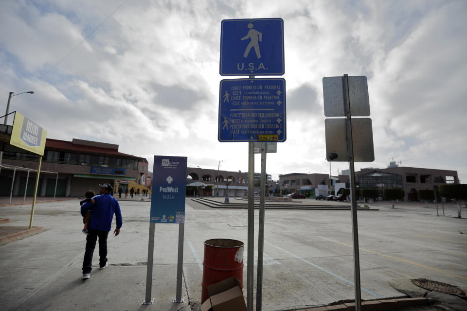 In this July 10, 2019, photo, Juan Carlos Perla, passes a sign leading to the border as he travels with his family from their home in Tijuana, Mexico, for an asylum hearing in San Diego. The Perlas are faring better than most of the roughly 60,000 asylum-seekers returned to Mexico under a Trump administration policy, many of whom live in fear of being robbed, assaulted, raped or killed. (AP Photo/Gregory Bull)