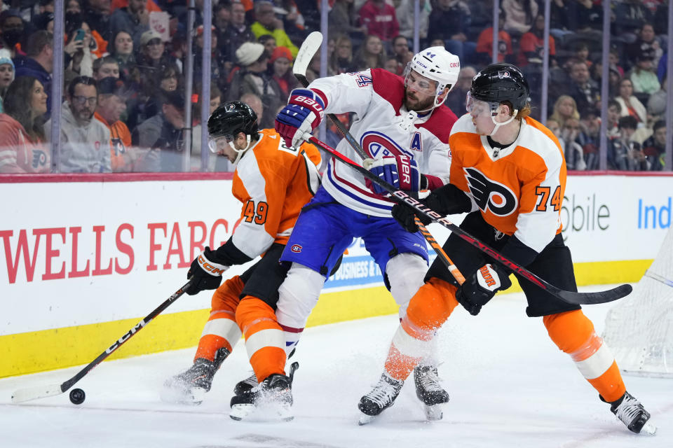 Montreal Canadiens' Joel Edmundson (44) battles for the puck against Philadelphia Flyers' Owen Tippett (74) and Noah Cates (49) during the second period of an NHL hockey game, Tuesday, March 28, 2023, in Philadelphia. (AP Photo/Matt Slocum)