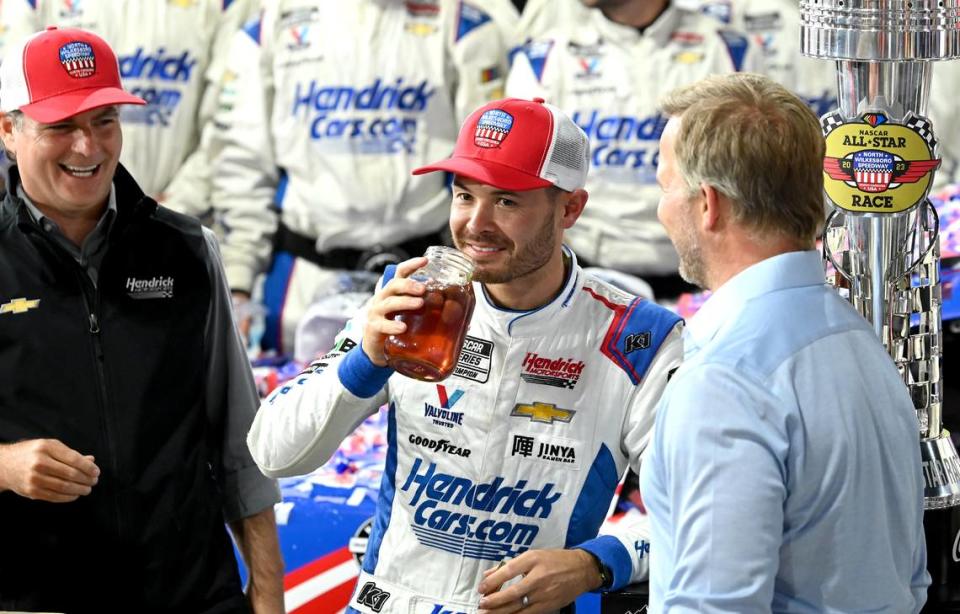 NASCAR driver Kyle Larson, center, takes a swig of moonshine in victory lane as former driver Jeff Gordon, left and Marcus Smith, CEO of Speedway Motorsports, right, look on as the team celebrate winning the NASCAR All-Star race at North Wilkesboro Speedway on Sunday, May 21, 2023. JEFF SINER/jsiner@charlotteobserver.com