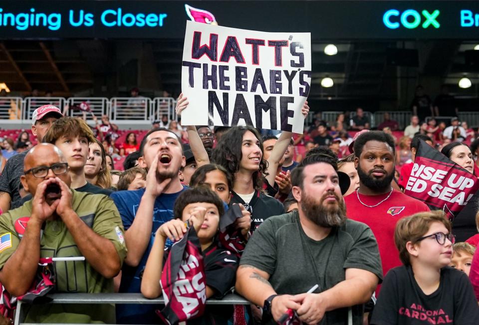 A fan holds up a sign at State Farm Stadium in Glendale on July 30, 2022, in reference to Arizona Cardinals defensive end J.J. Watts (99) and his wife Kealia Ohai’s recent announcement that they are expecting their first child.
