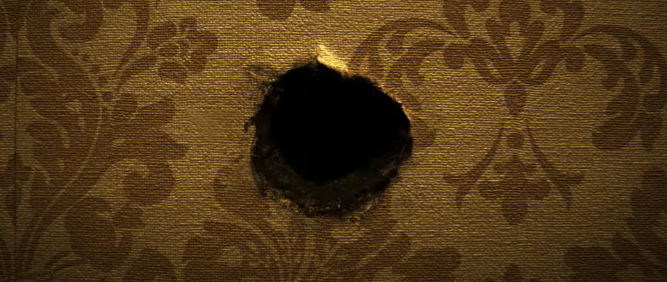 A large hole is visible in a textured wall with a patterned design