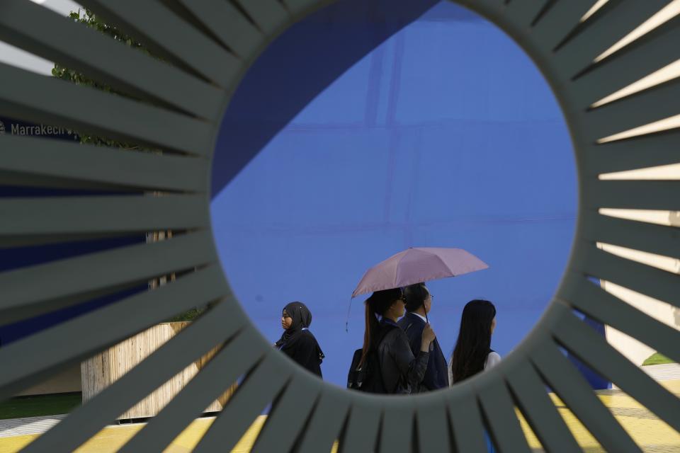A woman walks with an umbrella to shield herself from the sun during the COP28 U.N. Climate Summit, Saturday, Dec. 9, 2023, in Dubai, United Arab Emirates. (AP Photo/Peter Dejong)