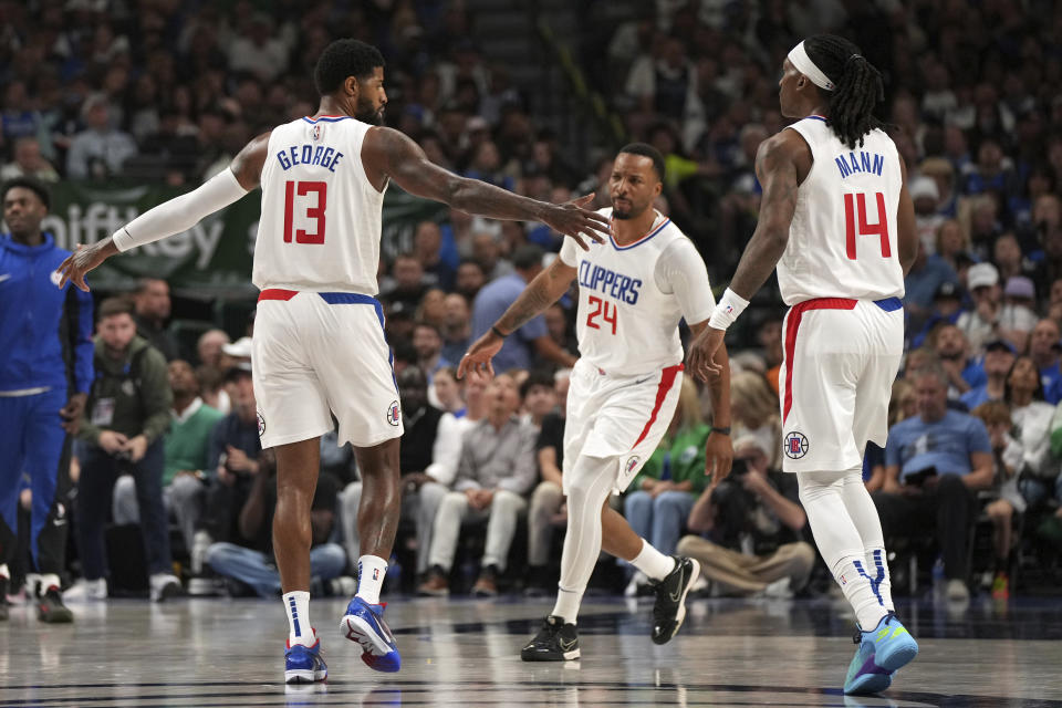 Los Angeles Clippers forward Paul George (13), guard Terance Mann (14) and guard Norman Powell (24) celebrate after a basket during the first half of Game 4 of an NBA basketball first-round playoff series against the Dallas Mavericks, Sunday, April 28, 2024, in Dallas. (AP Photo/Jeffrey McWhorter)