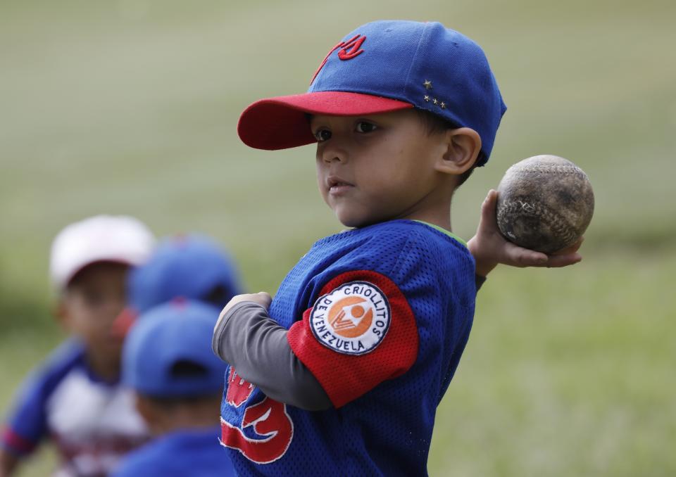 In this Aug. 12, 2019 photo, a young baseball player winds up to throw a ball during a practice at Las Brisas de Petare Sports Center, in Caracas, Venezuela. Venezuela was an incubator of Major League Baseball stars such as Miguel Cabrera and Felix Hernandez, but now the troubled country is struggling to showcase emerging talent. Kids face obstacles just to get on the field and play. (AP Photo/Ariana Cubillos)