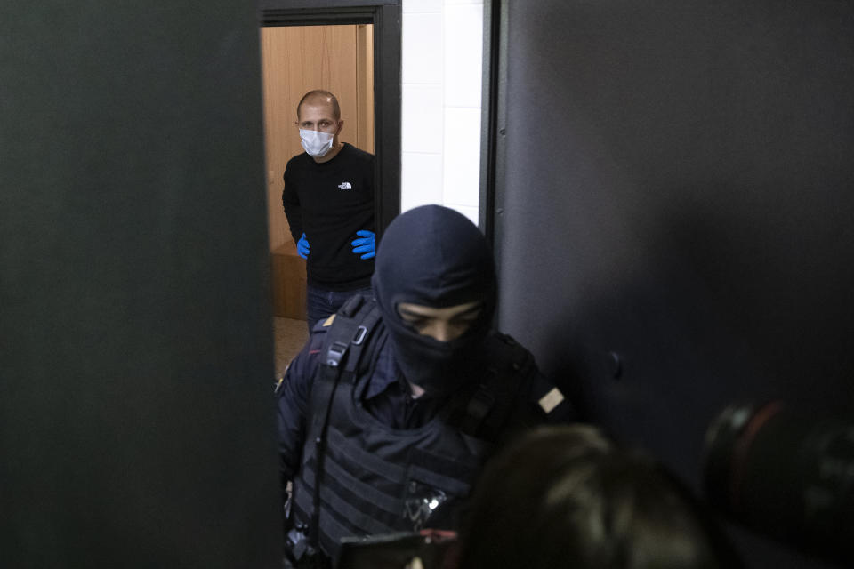 A police officer and an investigator stands behind the door of the apartment of jailed opposition leader Alexei Navalny in Moscow, Russia, Wednesday, Jan. 27, 2021. Police are searching the Moscow apartment of jailed Russian opposition leader Alexei Navalny, another apartment where his wife is living and two offices of his anti-corruption organization. Navalny's aides reported the Wednesday raids on social media. (AP Photo/Pavel Golovkin)