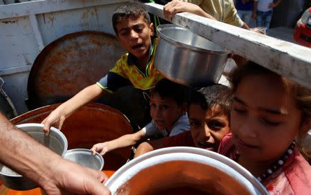 Displaced Iraqi civilians hold pots for free food at the Old City in Mosul, Iraq June 29, 2017. REUTERS/Erik De Castro