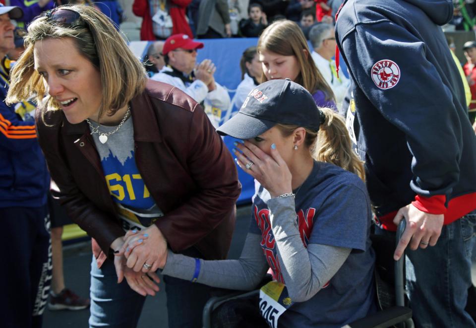 Survivor Rebekah Gregory DiMartino, center, wipes tears as she is led in her wheelchair after crossing the finish line of the Boston Marathon Tribute Run in Boston, Saturday, April 19, 2014. (AP Photo/Elise Amendola)