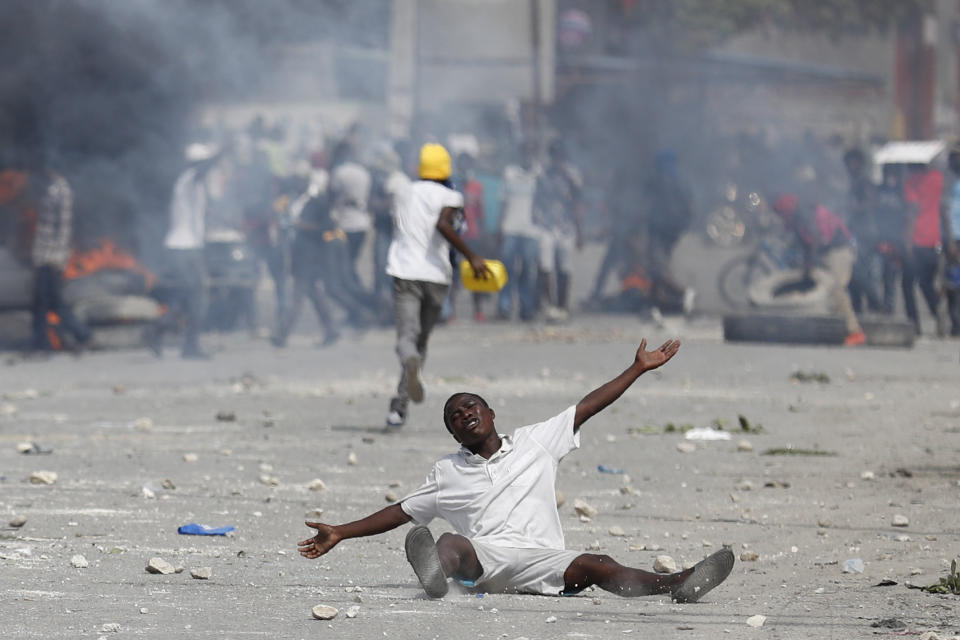 A protestor drops to the ground as he pleads with police after they fired tear gas to prevent protestors from marching toward the United Nations headquarters, in Port-au-Prince, Haiti, Friday, Oct. 4, 2019. Thousands of protesters marched through the Haitian capital to the U.N. headquarters Friday in one of the largest demonstrations in a weekslong push to oust the embattled President Jovenel Moise. (AP Photo/Rebecca Blackwell)