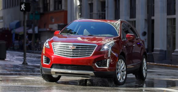 A red Cadillac XT5, a midsize crossover SUV, on a city street.