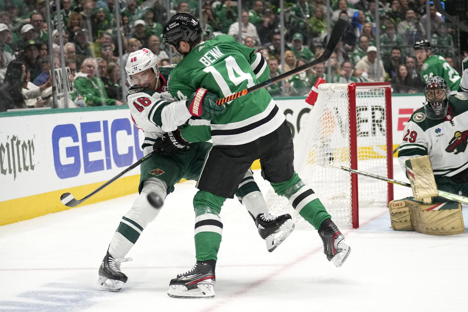 Minnesota Wild defenseman Jared Spurgeon (46) clears the puck before being hit b y Dallas Stars' Jamie Benn (14) in the first period of Game 2 of an NHL hockey Stanley Cup first-round playoff series, Wednesday, April 19, 2023, in Dallas. (AP Photo/Tony Gutierrez)