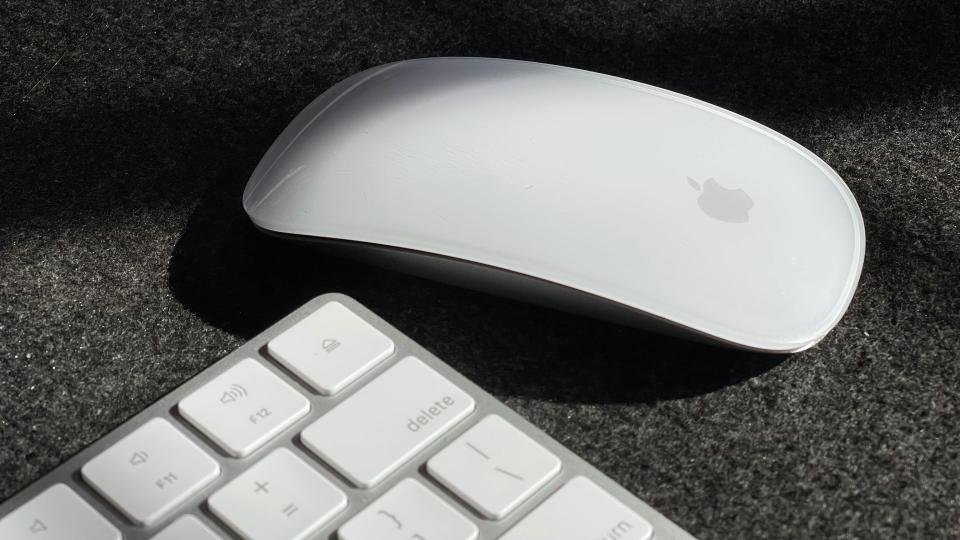 A Magic Mouse on a desk next to a Magic Keyboard.