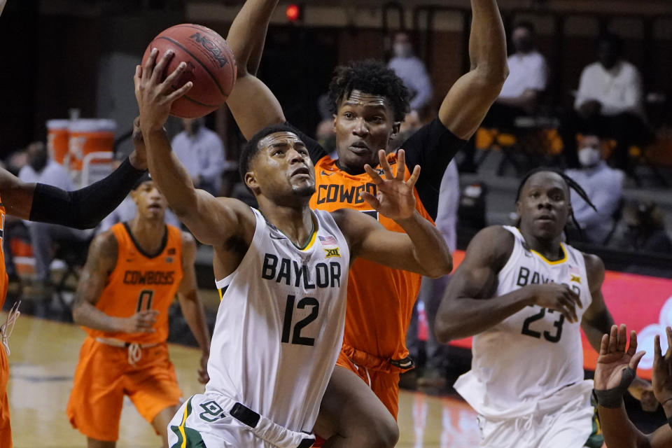 Baylor guard Jared Butler (12) goes to the basket in front of Oklahoma State forward Matthew-Alexander Moncrieffe, rear, in the first half of an NCAA college basketball game Saturday, Jan. 23, 2021, in Stillwater, Okla. (AP Photo/Sue Ogrocki)